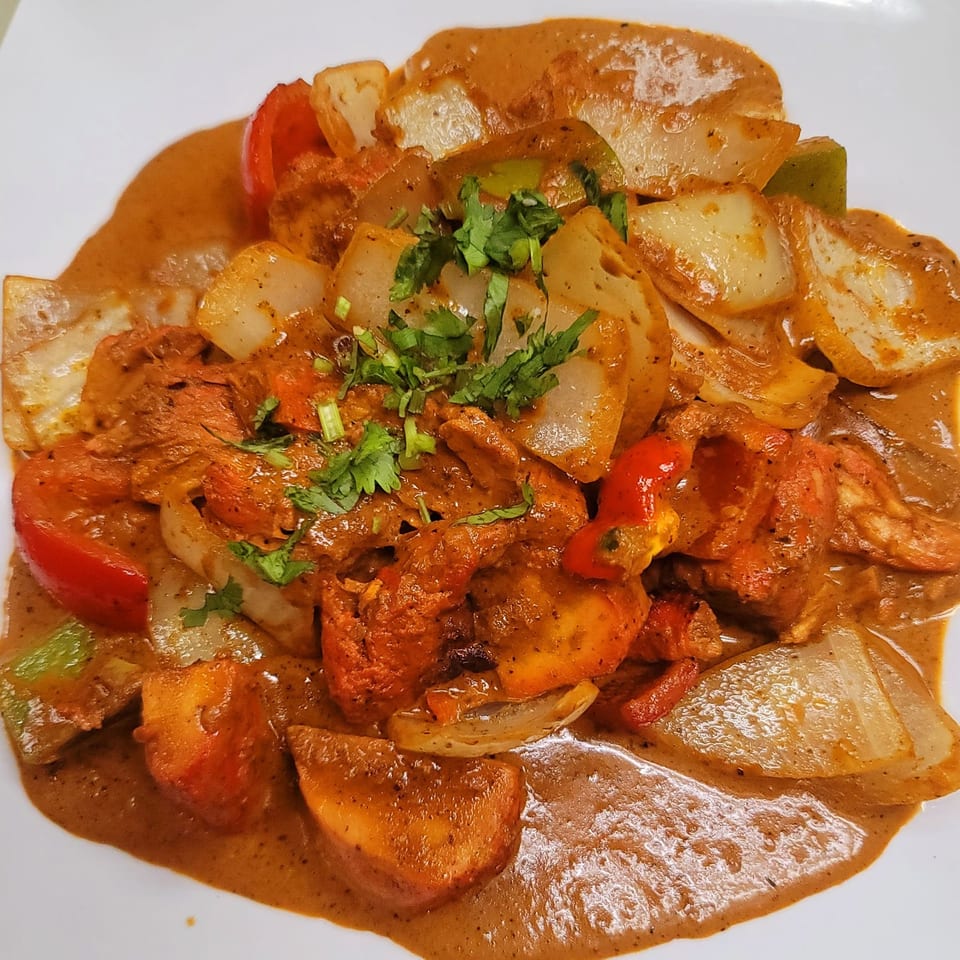 Sherpa Grill's chicken tikka masala with bell peppers, onions, and cilantro on a white plate.